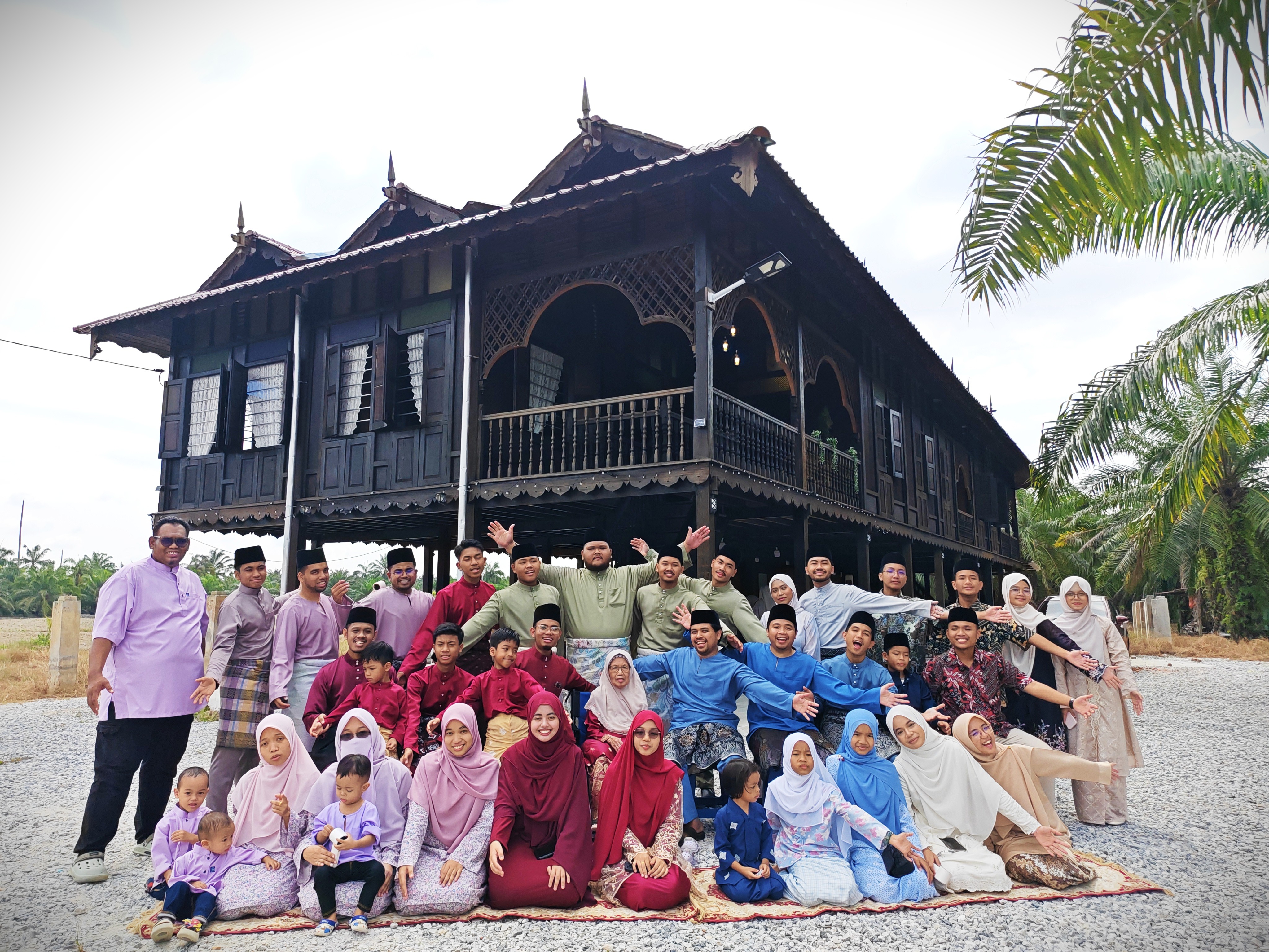 Rumah Melayu tradisional berbumbung tinggi dikelilingi pokok kelapa pada waktu senja