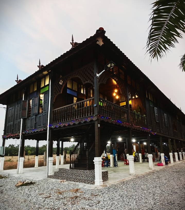 Wajah luar rumah homestay dengan tangga kayu dan beranda yang teduh